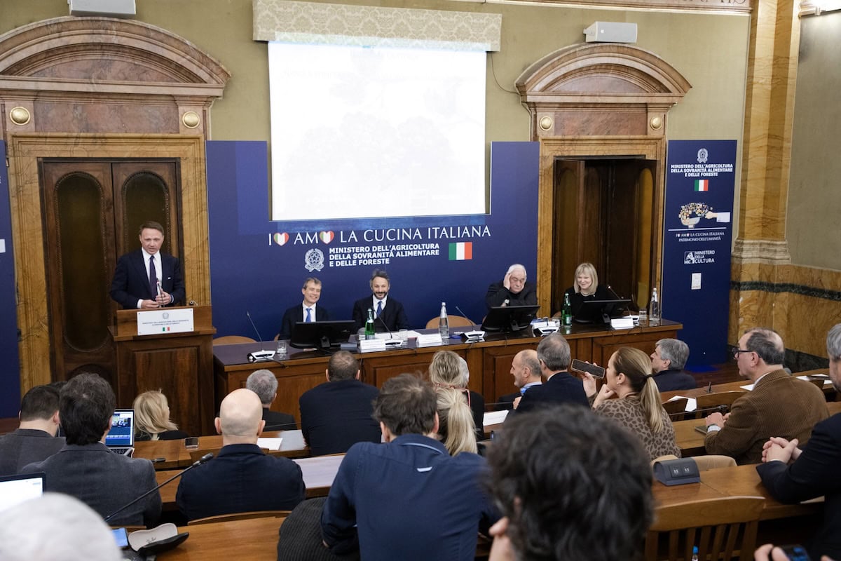 Conferenza stampa al Ministero dell’Agricoltura per la presentazione del progetto vitivinicolo di Pompei. Il Ministro Francesco Lollobrigida parla al podio, mentre i relatori Gabriel Zuchtriegel e Antonio Capaldo siedono al tavolo centrale. Sullo sfondo è visibile il logo "I ❤️ AMO LA CUCINA ITALIANA" e uno schermo con le immagini dei vitigni.