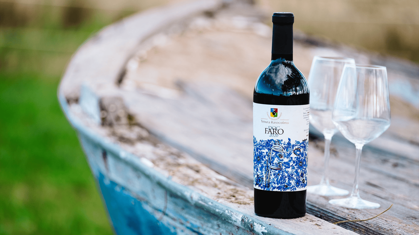Immagine di una bottiglia di Faro DOC 2020 Tenuta Rasocolmo e due calici vuoti pronti per essere riempiti.