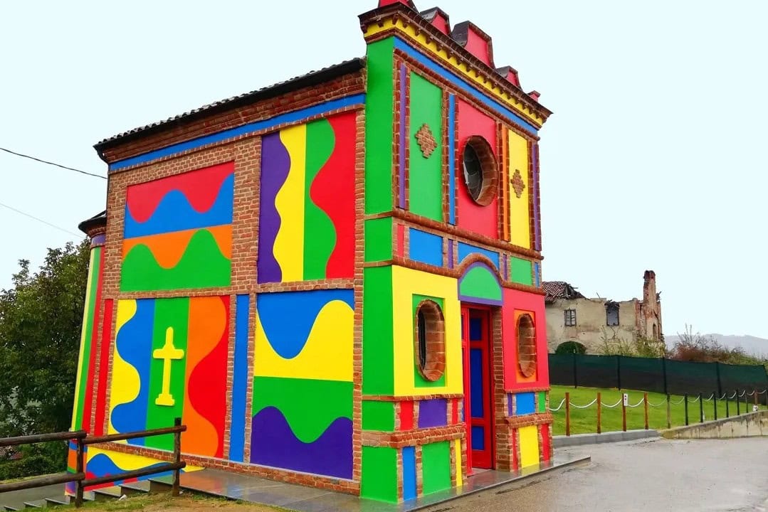 La famosa Cappella del Barolo a La Morra, caratterizzata dalle vivaci facciate esterne dipinte con colori accesi e forme geometriche astratte dall'artista Sol LeWitt, immersa nel paesaggio delle Langhe.